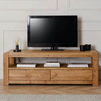 Wooden TV stand with a television on top against a white wall.