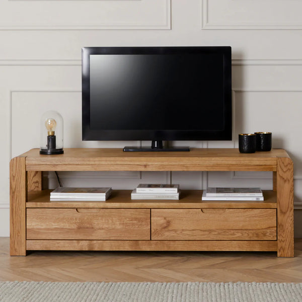 Wooden TV stand with a television on top against a white wall.