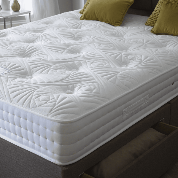 White mattress on a bed with green pillows in a room setting.
