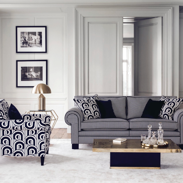 Modern living room with patterned sofa and armchair, coffee table, and decorative items.