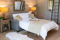 Cozy bedroom with a bed, sofa, and decorative lamps.