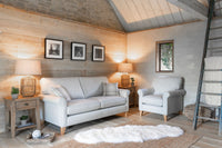 Cozy living room with grey sofa, armchair, and wooden furniture.