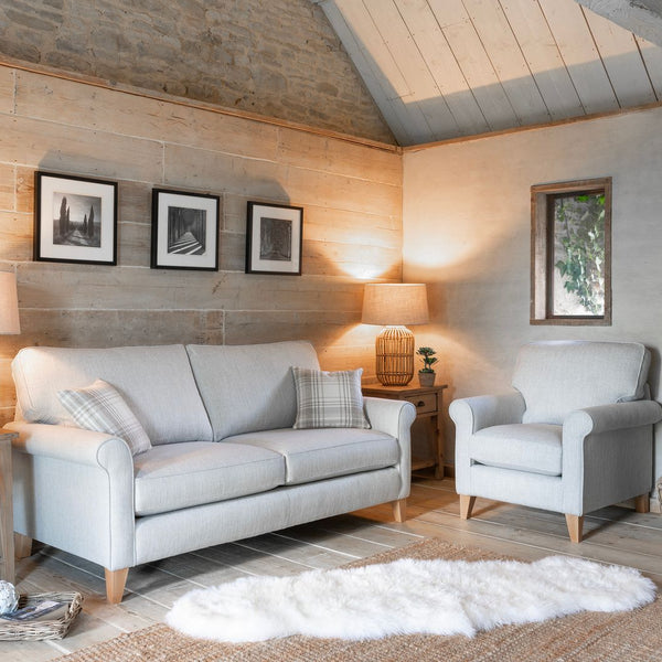 Cozy living room with grey sofa, armchair, and wooden furniture.