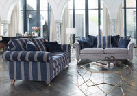 Two sofas, one striped and one grey with blue scatter cushions, in a modern living room.