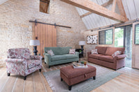 Living room with brick walls, wooden beams, and comfortable furniture.