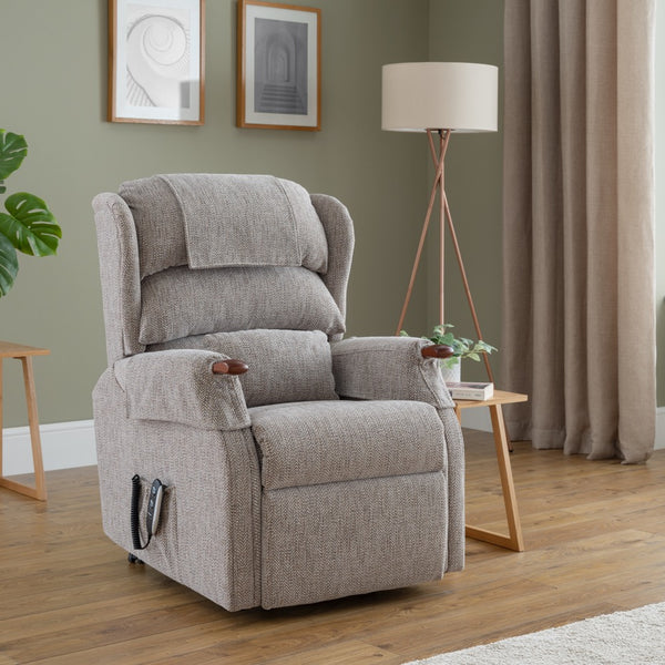 Grey recliner chair in a living room setting with a plant, side table, and lamp.