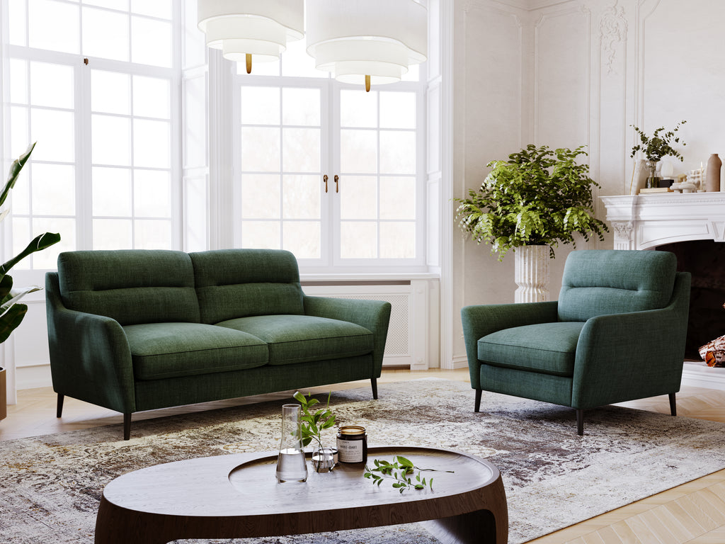 Modern living room with green sofa and armchair, round coffee table, and decorative elements.