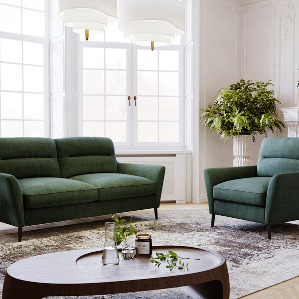 Modern living room with green sofa and armchair, round coffee table, and decorative elements.