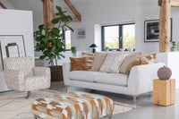 Modern living room with a grey sofa, patterned armchair, and footstool.